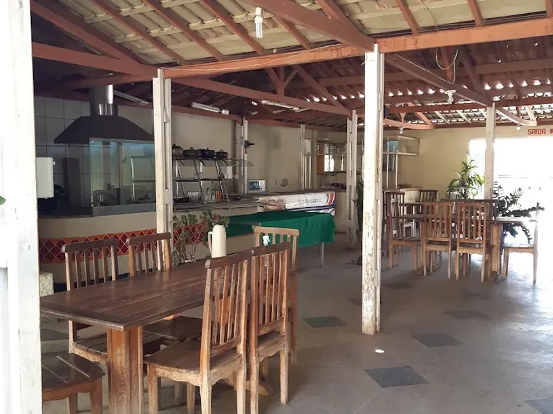 Área coberta com mesas e bancos de madeira, usada para o café da manhã